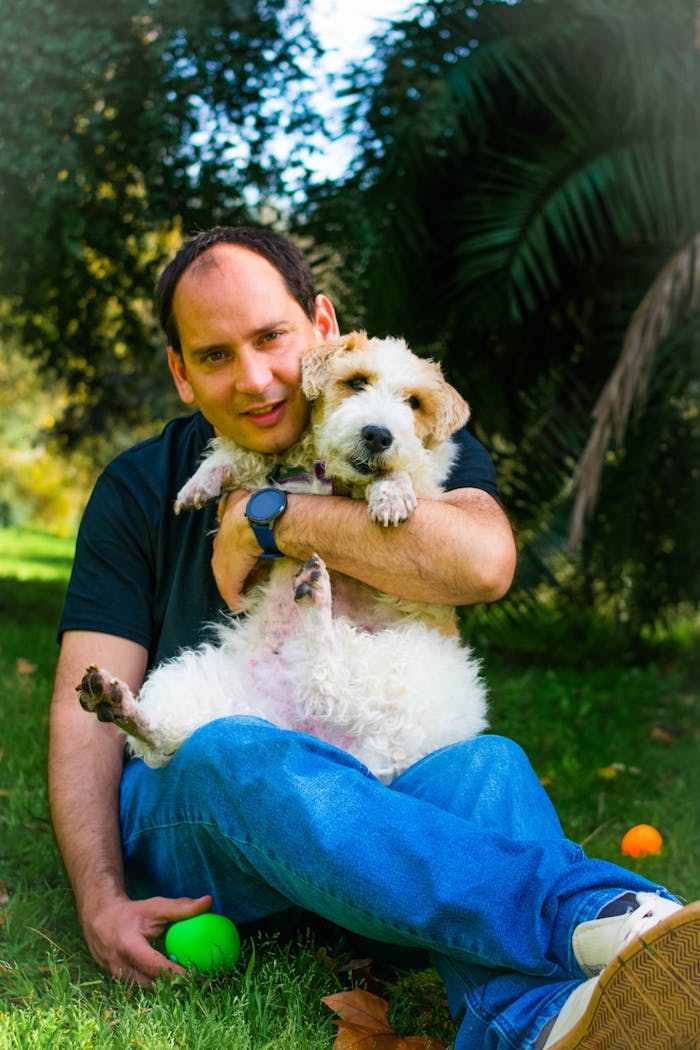 uśmiechnięty mężczyzna pozujący do zdjęcia z puszystym pieskiem uśmiechnięty mężczyzna pozujący do zdjęcia z puszystym pieskiem